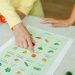 Close-up of hands pointing to a vegetable nutrition chart with fresh tomatoes on the table.