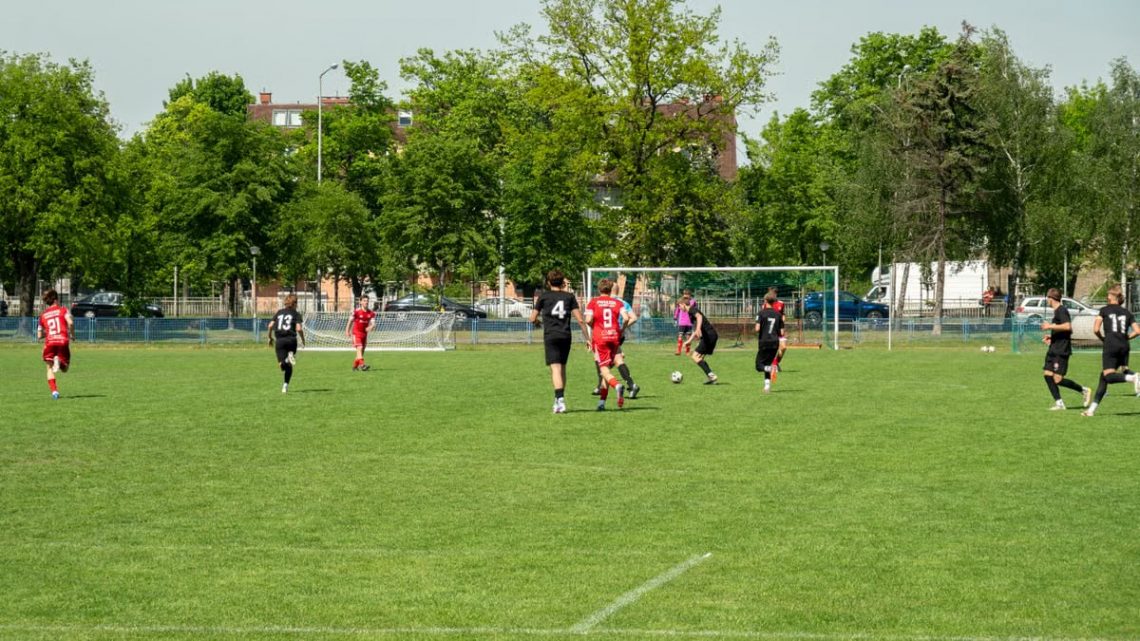 Amateur soccer players compete in a local match at a grassy field in Wrocław, Poland.