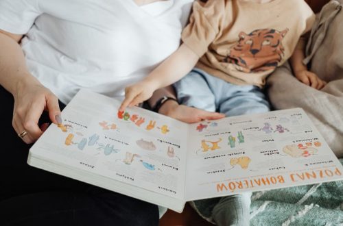 A mother and her son enjoy reading a children's book together while sitting on a cozy couch.